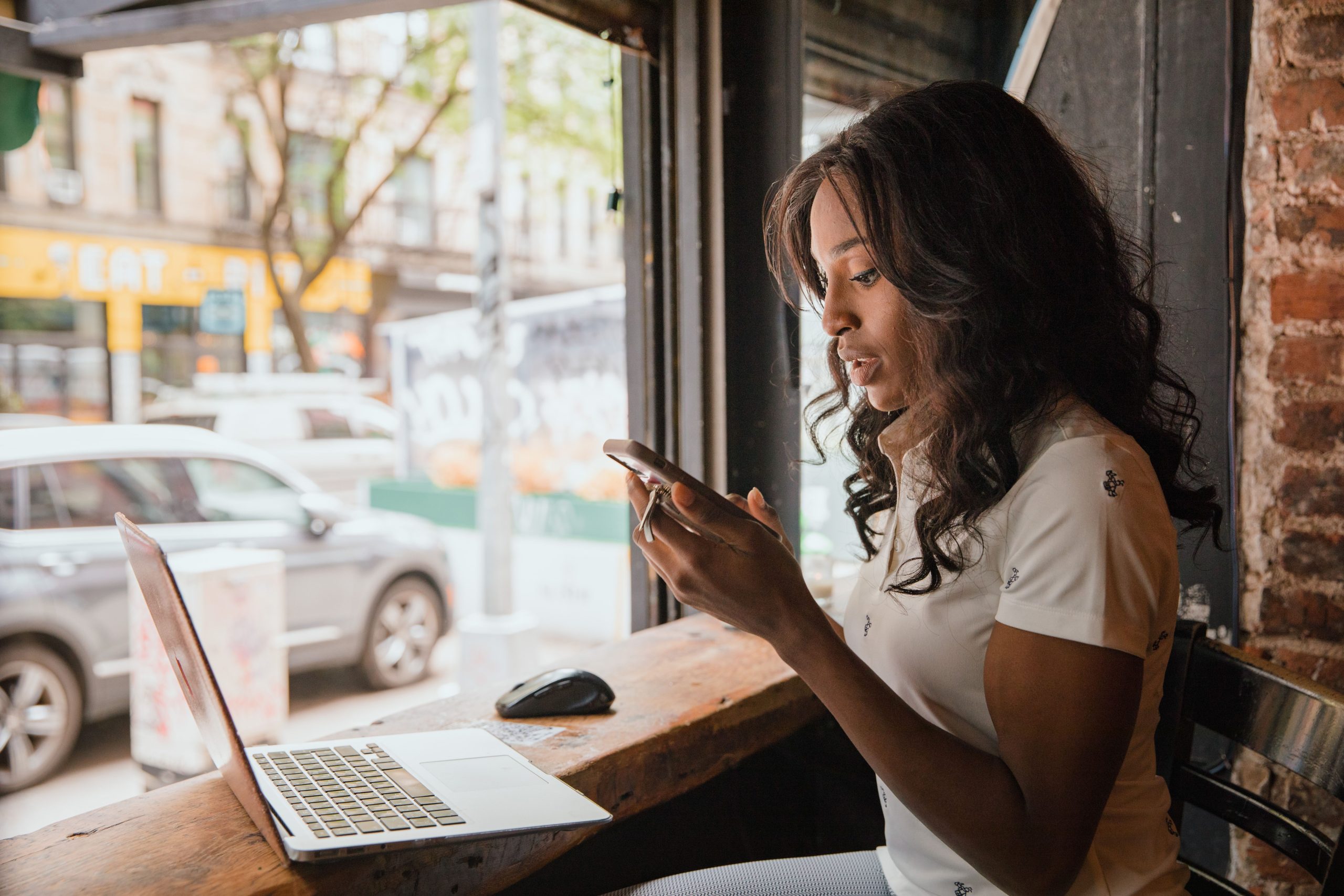 Employee working from a cafe with a laptop and smartphone.
