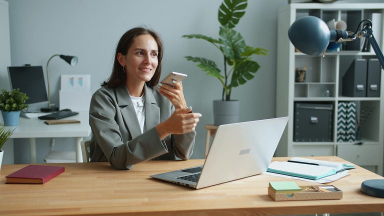 Employee using a laptop and smartphone for work.