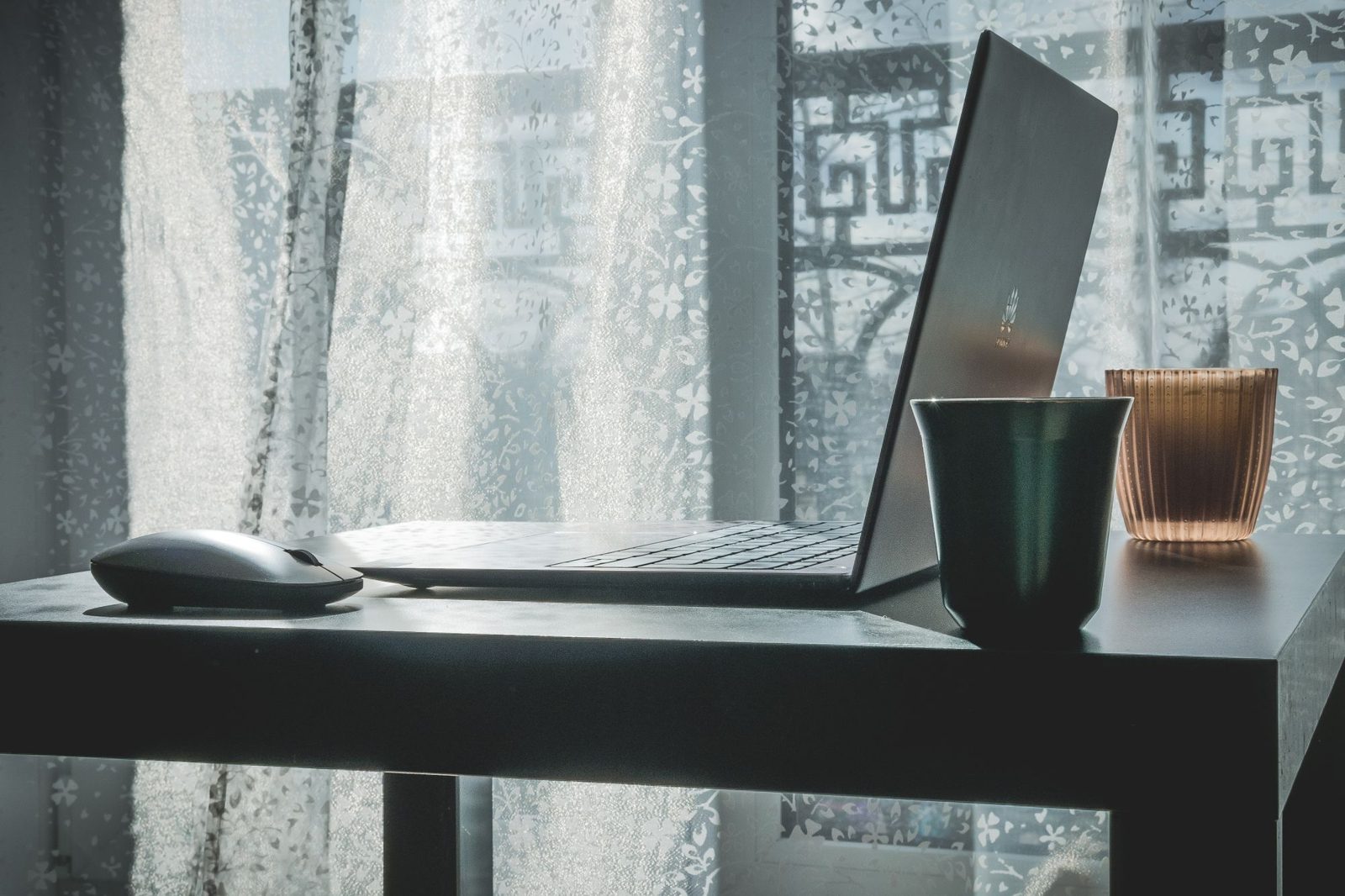 Modern laptop and wireless mouse on an office desk.